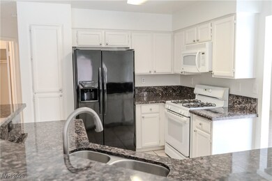Kitchen with white appliances, dark stone countert