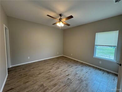Empty room featuring dark wood finished floors, ceiling fan, and baseboards