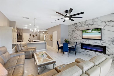 Living area featuring a ceiling fan, a chandelier, a premium fireplace, and baseboards