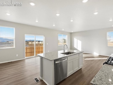Kitchen featuring light stone countertops, dark wood-type flooring, open floor plan, stainless steel dishwasher, and recessed lighting