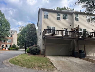 Back of property with a wooden deck, driveway, and a garage