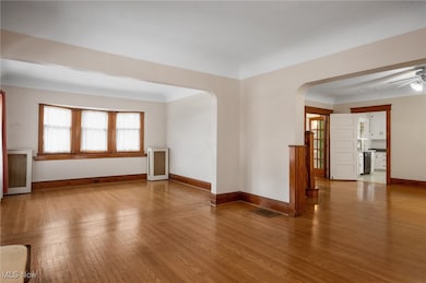 Spare room with wood-type flooring, arched walkways, radiator, ceiling fan, and beverage cooler