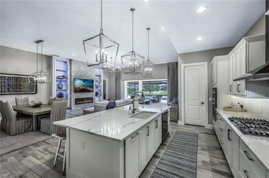 Kitchen with white cabinetry, a chandelier, a breakfast bar, a center island with sink, and decorative light fixtures