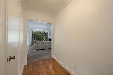 Hallway featuring wood-type flooring and crown mol