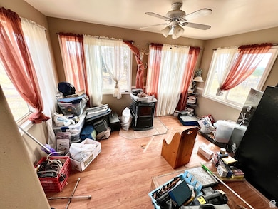 Office area with a wood stove, light wood finished floors, plenty of natural light, and ceiling fan