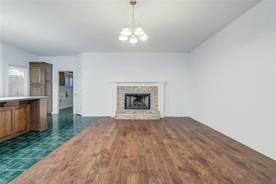 Unfurnished living room featuring a chandelier, a fireplace, and dark wood-type flooring