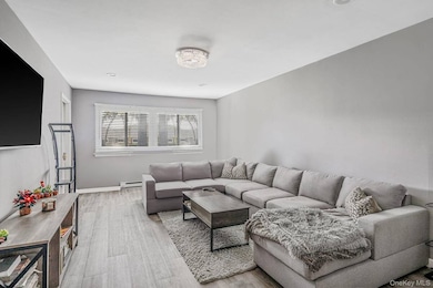 Living area with light wood-type flooring and a baseboard radiator
