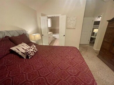 Carpeted bedroom with connected bathroom and a high ceiling