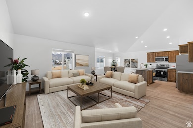 Living room featuring vaulted ceiling, recessed lighting, and light wood-style floors