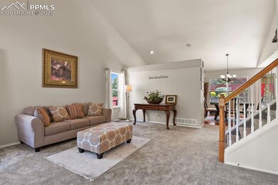 Living area with a chandelier, carpet floors, healthy amount of natural light, high vaulted ceiling, and stairway