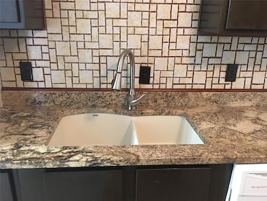 Kitchen view of decorative backsplash and dark stone countertops
