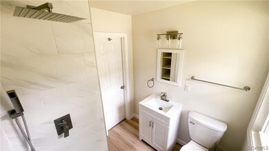 Hallway Bathroom featuring vanity, toilet, and hardwood / wood-style flooring