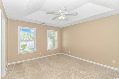 Empty room featuring light colored carpet, baseboards, a textured ceiling, and a ceiling fan