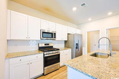 Kitchen with stainless steel appliances, white cabinetry, backsplash, light stone counters, and recessed lighting