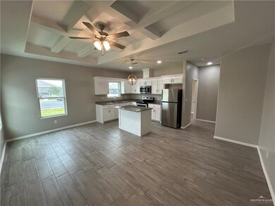 Kitchen with appliances with stainless steel finishes, dark countertops, baseboards, ceiling fan, and dark wood finished floors