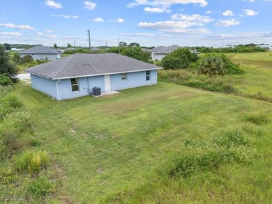 Rear view of property featuring a yard, stucco siding, and a shingled roof