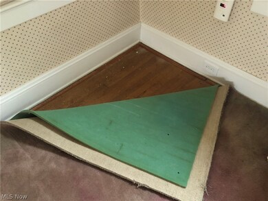 corner of carpeet pulled back to show hardwood flooring believed to be under the entire room