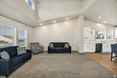 Living area with light carpet, high vaulted ceiling, and recessed lighting