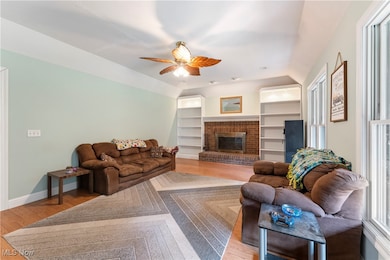 Living area featuring light wood-type flooring, a fireplace, and lofted ceiling