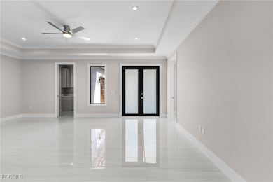 Unfurnished room with french doors, a raised ceiling, ornamental molding, a ceiling fan, and recessed lighting