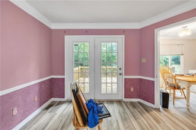Doorway to outside featuring wood finished floors, plenty of natural light, baseboards, and ornamental molding