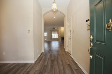 Foyer with a fireplace, a ceiling fan, dark wood-type flooring, arched walkways, and recessed lighting
