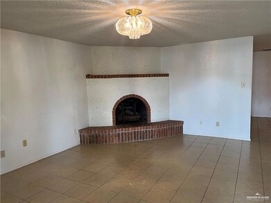 Unfurnished living room with an inviting chandelier, a brick fireplace, tile patterned flooring, and a textured ceiling