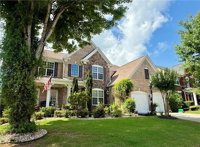 Traditional-style house with an attached garage, a front yard, brick siding, and driveway