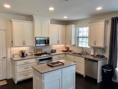 Kitchen with white cabinets, backsplash, dark wood