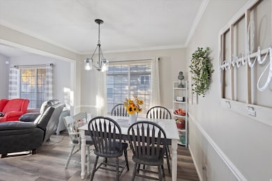 Dining space featuring dark wood-style flooring, ornamental molding, and a chandelier