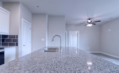 Kitchen with white cabinets, ceiling fan, stone co