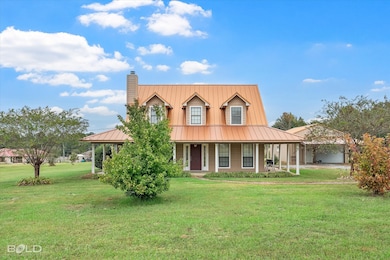 Farmhouse with a front lawn, a porch, a chimney, and a metal roof