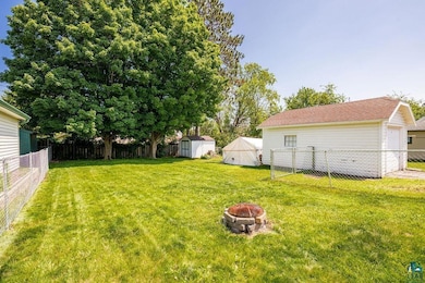 Fenced backyard featuring an outdoor fire pit, a storage shed, and a detached garage