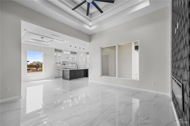 Unfurnished living room with marble finish floor, ceiling fan, baseboards, and a raised ceiling