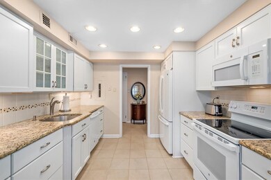 Kitchen has white cabinetry and granite countertop