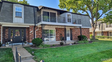 View of front of home featuring a balcony, a front yard, mansard roof, and brick siding