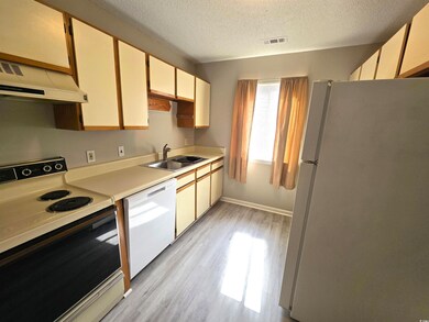 Kitchen with a textured ceiling, white appliances,