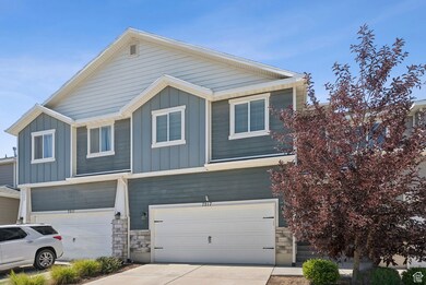 View of front facade with board and batten siding, stone siding, driveway, and a garage