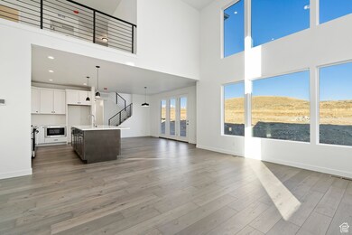 Unfurnished living room with a towering ceiling, stairs, and light wood-type flooring