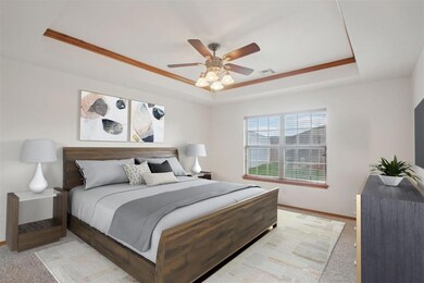 Bedroom with a tray ceiling, light colored carpet,