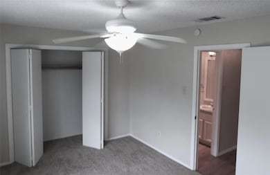 Unfurnished bedroom with a textured ceiling, carpet floors, a closet, and ceiling fan