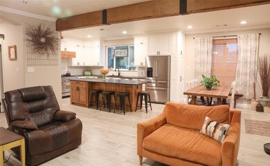 Living room featuring beamed ceiling, light hardwo