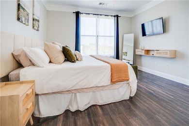 Bedroom featuring ornamental molding, dark wood-style flooring, and ceiling fan