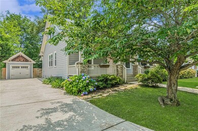 Obstructed view of property featuring an outbuilding, driveway, a front yard, a detached garage, and covered porch