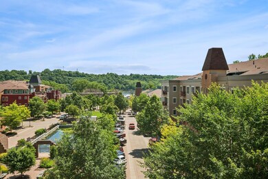 A river view plus a charming blend of colorful, multi-story buildings with warm-toned facades, large windows; gabled and turret-style roofs that give the area a quaint, village-like feel.