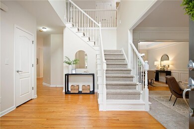 Step into a two-story foyer flooded with natural light and newly refreshed hardwood floors.