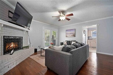 Living room with ceiling fan, wood finished floors, a fireplace, plenty of natural light, and ornamental molding