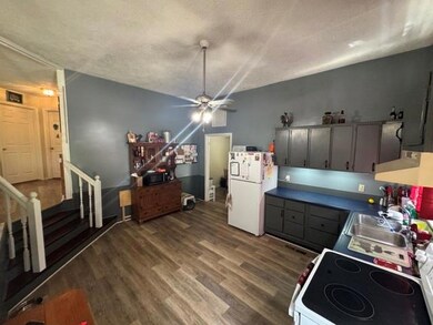 Kitchen featuring freestanding refrigerator, range hood, wood finished floors, a ceiling fan, and range