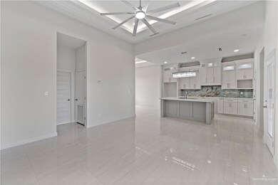 Kitchen with hanging light fixtures, an island with sink, ceiling fan, backsplash, and sink