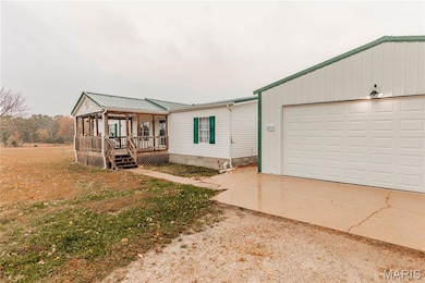 View of front facade with a metal roof, a garage, crawl space, and driveway